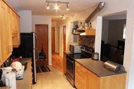 Montréal apartment for rent - A kitchen with wooden cabinets and a black refrigerator.