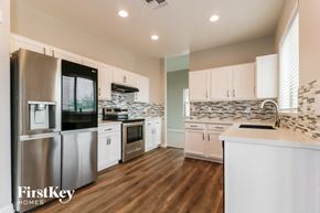 Buckeye house for rent - a kitchen with white cabinets and stainless steel appliances