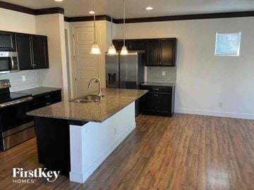 Brighton house for rent - an open kitchen with black cabinets and a granite counter top