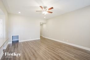 Clarksville house for rent - A spacious room with a ceiling fan and light fixture, and a wood floor.