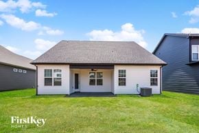 Clarksville house for rent - A small white house with a grey roof is surrounded by a grassy lawn.