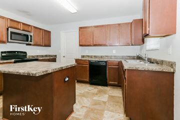 Covington house for rent - A kitchen with brown cabinets and a black oven.