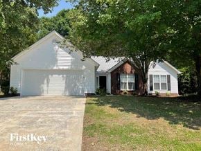 Charlotte house for rent - a white and brick house with a garage and trees