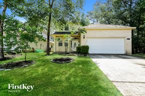 Montgomery house for rent - A house with a garage is surrounded by trees and has a well-maintained lawn.