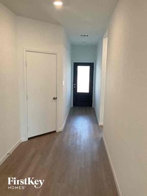 Bulverde house for rent - a hallway with white walls and a white door and wooden floors