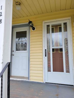 Stellarton apartment for rent - A white door with a glass window is on the right side of a yellow house.