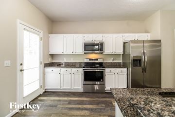 Winston-Salem house for rent - a kitchen with white cabinets and stainless steel appliances