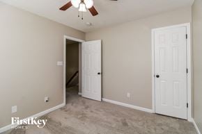 Winston-Salem house for rent - a bedroom with two doors and a carpeted floor and a ceiling fan