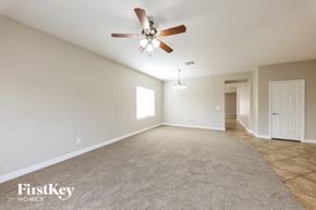 Laveen house for rent - A spacious room with a ceiling fan and light fixture, carpeted floor, and a door on the right.