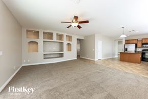 Laveen house for rent - A spacious living room with a ceiling fan and built-in shelves.