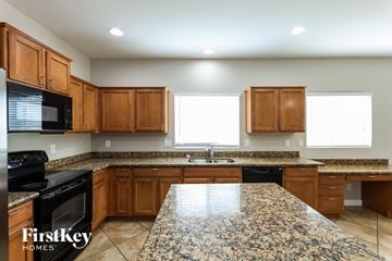Laveen house for rent - A kitchen with granite countertops and wooden cabinets.