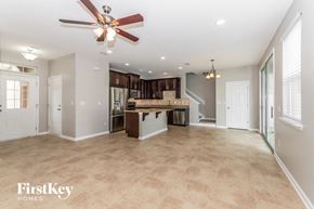 Jacksonville house for rent - an empty living room with a kitchen and a ceiling fan