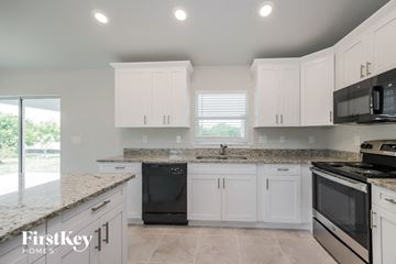Lehigh Acres house for rent - a kitchen with white cabinets and black appliances