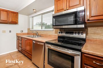Tucson house for rent - a kitchen with stainless steel appliances and wooden cabinets