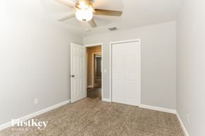 Jacksonville house for rent - a bedroom with a ceiling fan and a door to a hallway