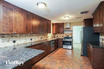 Cypress house for rent - A kitchen with brown cabinets and a black refrigerator.