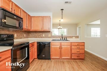 Ladson house for rent - A kitchen with wooden cabinets and a black dishwasher.