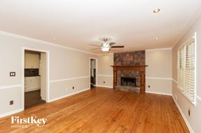 Canton house for rent - a living room with a fireplace and wooden floors and a ceiling fan