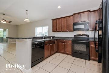 Davenport house for rent - A kitchen with a black fridge and stove top oven.