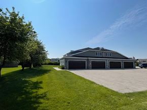 Belgium apartment for rent - A large house with a garage is surrounded by a green lawn.