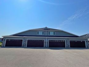 Belgium apartment for rent - A large two-story building with a grey roof and four garage doors.