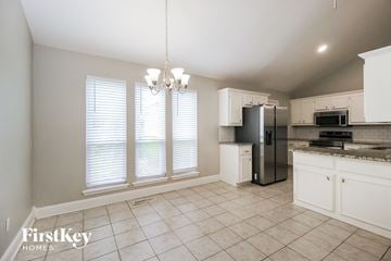 Norman house for rent - A kitchen with white cabinets and a black refrigerator.
