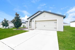 Dundee house for rent - A white house with a garage door is in front of a tree and other houses.