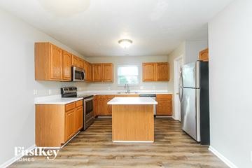 Indianapolis house for rent - A kitchen with wooden cabinets and a refrigerator.