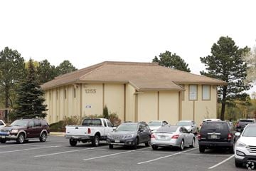 Colorado Springs apartment for rent - A parking lot with cars and a building with the number 1255.