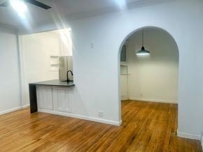 Dallas apartment for rent - an arched opening into a living room with wood flooring and a kitchen