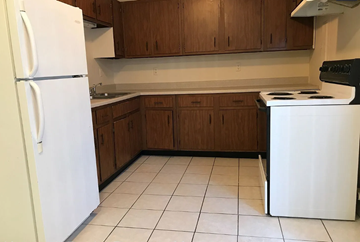 Lima apartment for rent - A white refrigerator stands in a kitchen with wooden cabinets.