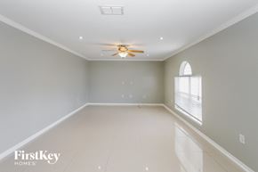 Deltona house for rent - A spacious room with a ceiling fan and a window with blinds.