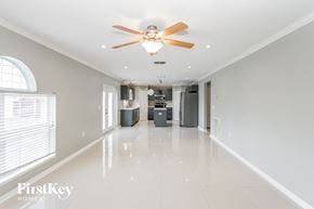 Deltona house for rent - A spacious, empty room with a ceiling fan and a large window.