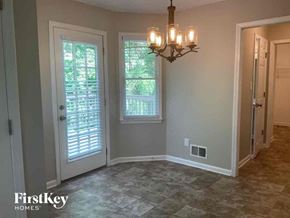 Douglasville house for rent - A room with a chandelier, two windows, and a door.