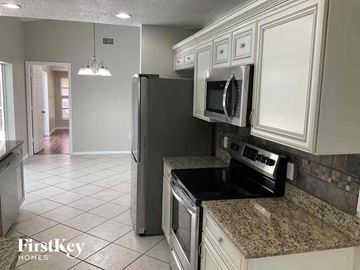 Port Charlotte house for rent - a kitchen with white cabinets and a stove and a refrigerator