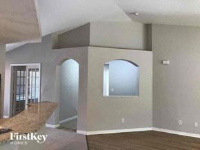 Cape Coral house for rent - an empty living room with an arched window and a kitchen