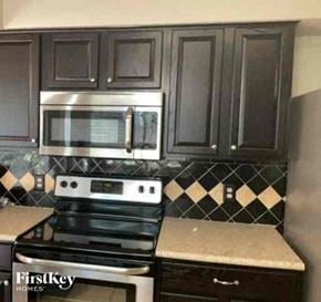Euless house for rent - a kitchen with black cabinets and a stove and a microwave