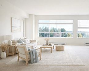 Ladysmith apartment for rent - A living room with a white sofa, a wooden chair, a coffee table, and a large window with a view of trees.
