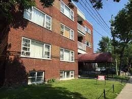 Montréal apartment for rent - a red brick apartment building with a green yard