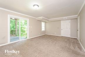 Lewisville house for rent - A spacious room with a carpeted floor and a sliding glass door leading to a garden.