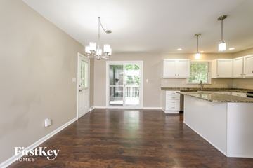 Lewisville house for rent - A spacious kitchen and living room with wooden floors and white cabinetry.