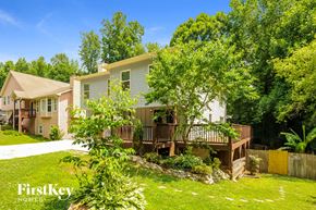 Sugar Hill house for rent - A house with a white exterior and a brown deck is surrounded by greenery.