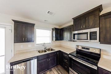 Tuscaloosa house for rent - a kitchen with black cabinets and stainless steel appliances