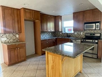 Santa Maria house for rent - A kitchen with wooden cabinets and a granite countertop.