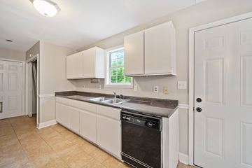 Jacksonville house for rent - A kitchen with white cabinets and a black dishwasher.