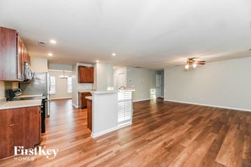 Summerville house for rent - an open kitchen and living room with wood flooring and a ceiling fan