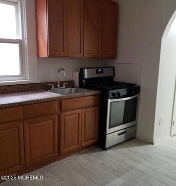 Keansburg apartment for rent - A kitchen with wooden cabinets and a black stove top oven.