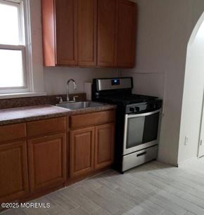 Keansburg apartment for rent - A kitchen with wooden cabinets and a black stove top oven.
