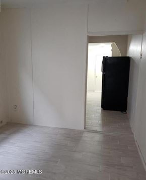 Keansburg apartment for rent - A black refrigerator is in a room with white walls and a tiled floor.