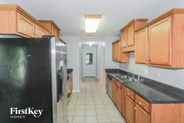 Memphis house for rent - a kitchen with wood cabinets and black counter tops and a refrigerator